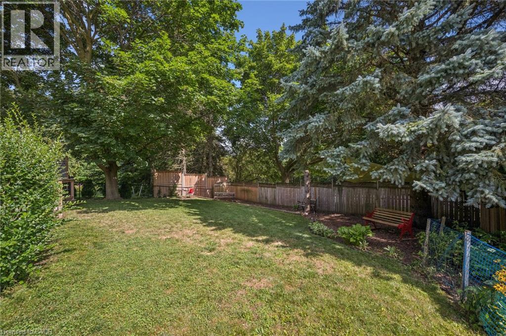 Expansive lawn area surrounded by mature trees, privacy fencing, and garden beds - 119 Sandy Ridge Place, Waterloo, ON - Outdoor