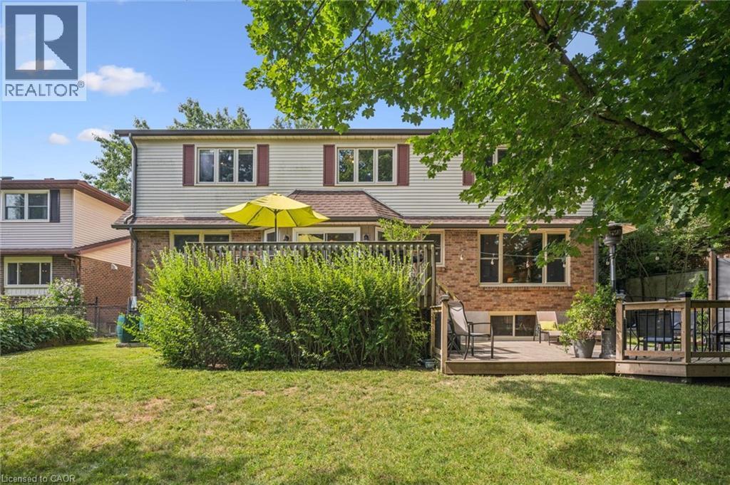 Expansive backyard featuring a manicured lawn, two-story home with brick and siding exterior, and a multi-level wood deck - 119 Sandy Ridge Place, Waterloo, ON - Outdoor