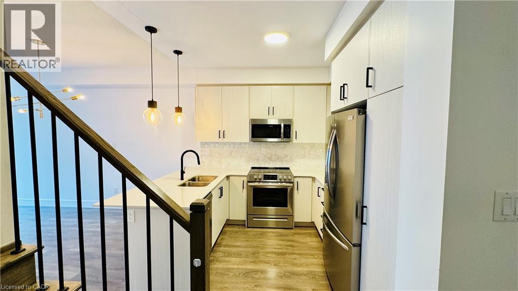 Kitchen featuring stainless steel appliances, light-toned cabinetry, light-toned countertops, and a tile backsplash - 1159 Lloyd Landing, Milton, ON - Indoor Photo Showing Kitchen With Double Sink