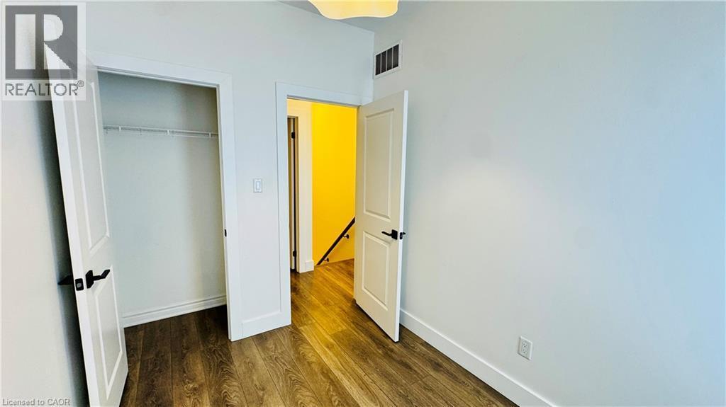 Wood-finish flooring with white baseboards and trim - 1159 Lloyd Landing, Milton, ON - Indoor Photo Showing Other Room