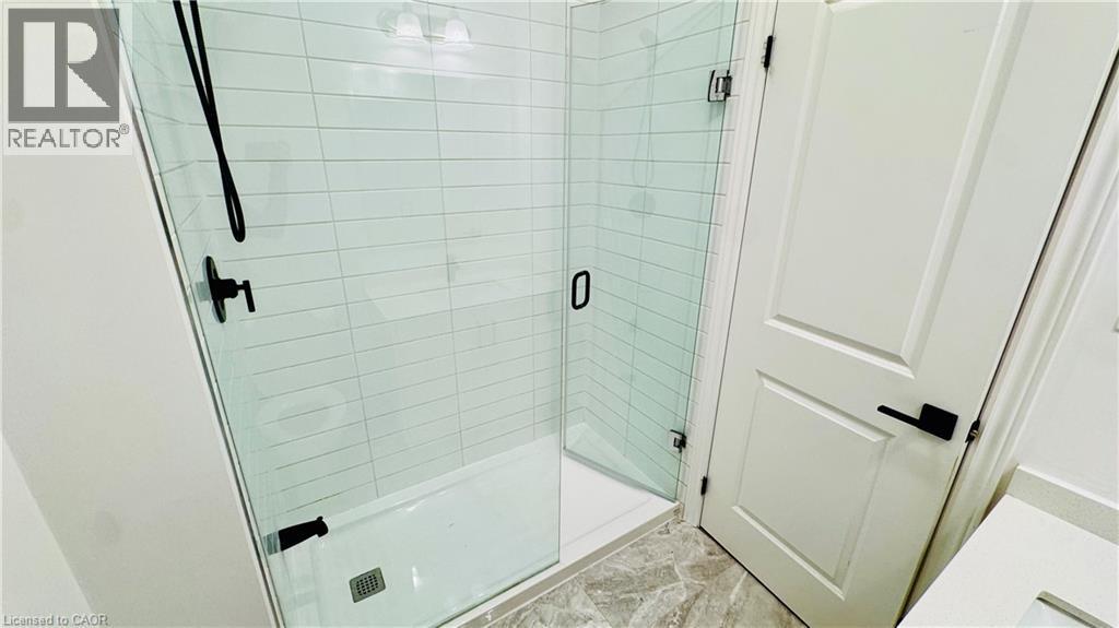 Frameless glass shower enclosure with matte black fixtures, white subway tile surround, and a white shower pan - 1159 Lloyd Landing, Milton, ON - Indoor Photo Showing Bathroom