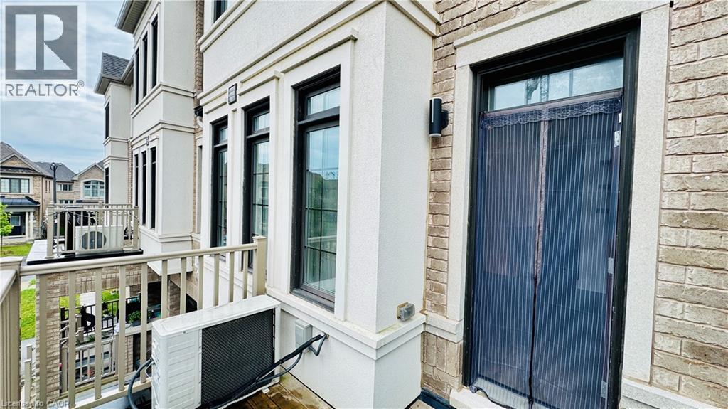 Brick and stucco exterior with multiple black-framed windows, a black exterior light fixture, and a balcony with a beige railing - 1159 Lloyd Landing, Milton, ON - Outdoor