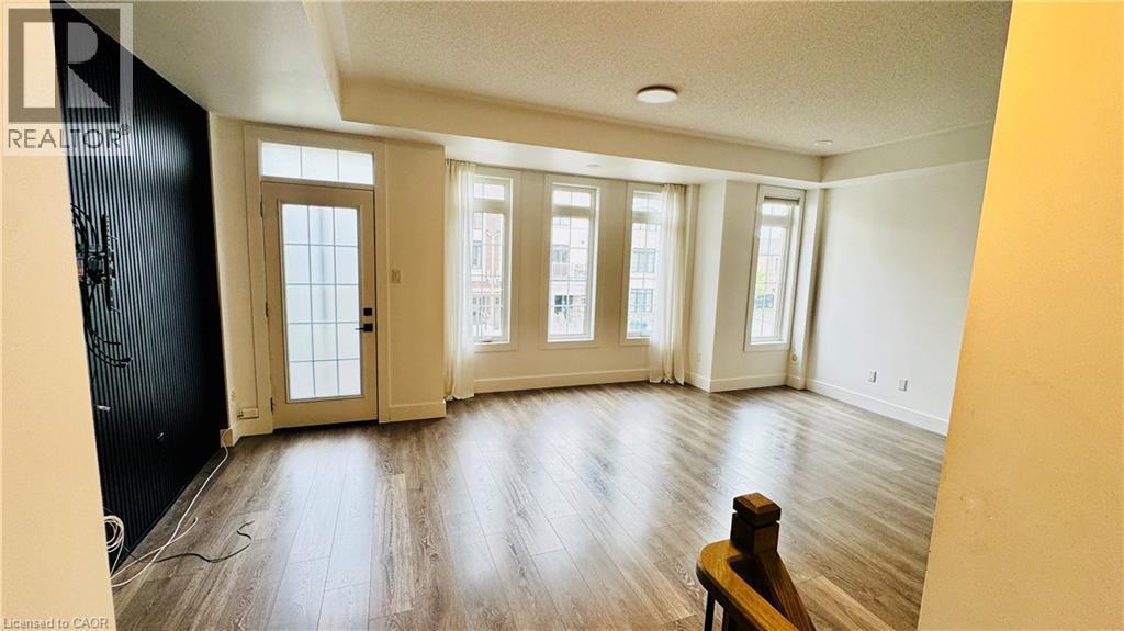 Recessed lighting, wood-finish flooring, a wall-mounted fixture, multiple large windows, and a glass-paneled door - 1159 Lloyd Landing, Milton, ON - Indoor Photo Showing Other Room