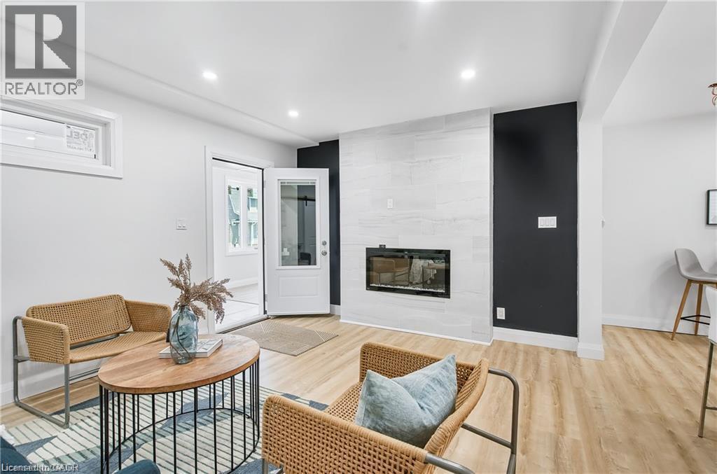 Living space featuring a contemporary fireplace with a light-toned tile surround, light wood-finish flooring, and recessed ceiling lighting - 10 Comet Avenue Unit# #1 (Main), Hamilton, ON - Indoor Photo Showing Living Room With Fireplace