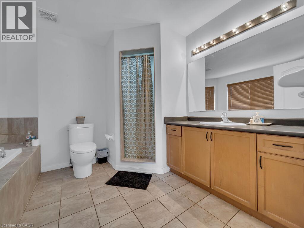 Bathroom featuring a vanity with light wood finish cabinetry, built-in sink, and a large mirror with strip lighting - 227 Baldwin Drive Unit# Main, Cambridge, ON - Indoor Photo Showing Bathroom