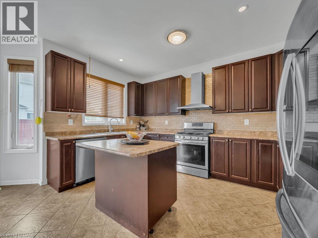 Kitchen featuring dark wood cabinetry, stainless steel appliances, a center island with a stone countertop, and tile flooring - 227 Baldwin Drive Unit# Main, Cambridge, ON - Indoor Photo Showing Kitchen