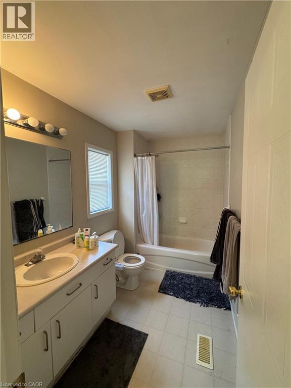 Bathroom featuring a single-sink vanity with white cabinetry, a built-in bathtub with shower, and tiled flooring - 720 Brookmill Place, Waterloo, ON - Indoor Photo Showing Bathroom