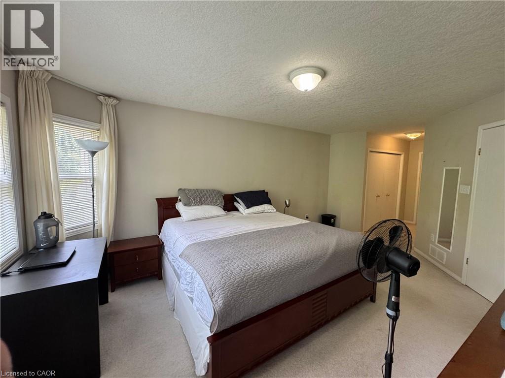 Hardwood-finish bed frame, light neutral wall color, built-in overhead lighting, light-colored carpeting, and window blinds - 720 Brookmill Place, Waterloo, ON - Indoor Photo Showing Bedroom
