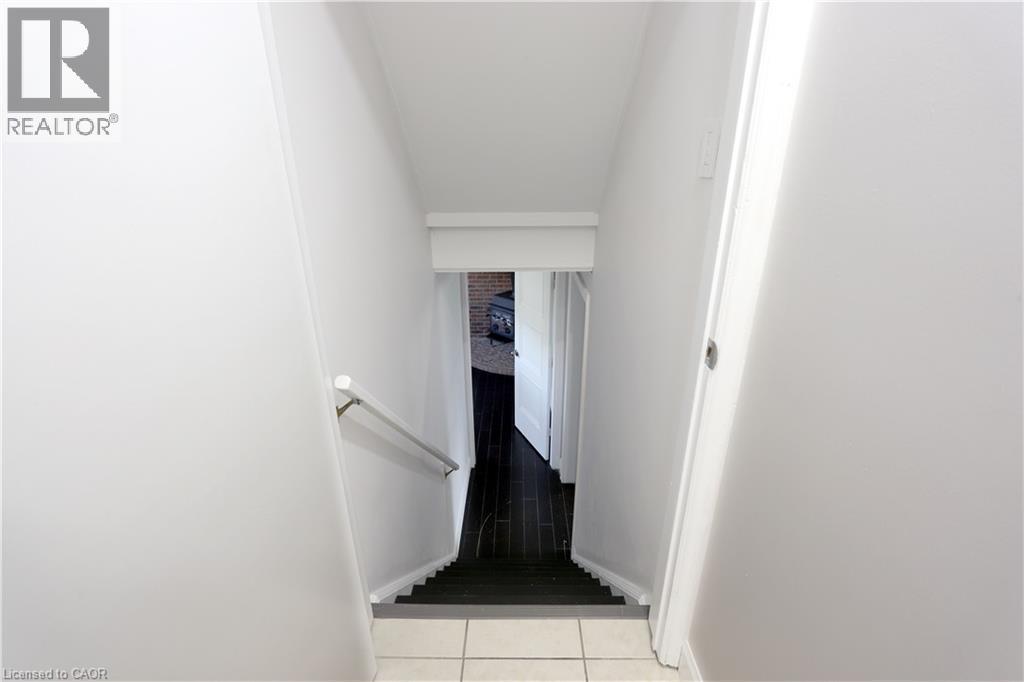 Staircase featuring a white handrail, light-toned wall finishes, and dark-toned treads - 77 Orchard Mill Crescent, Kitchener, ON - Indoor Photo Showing Other Room