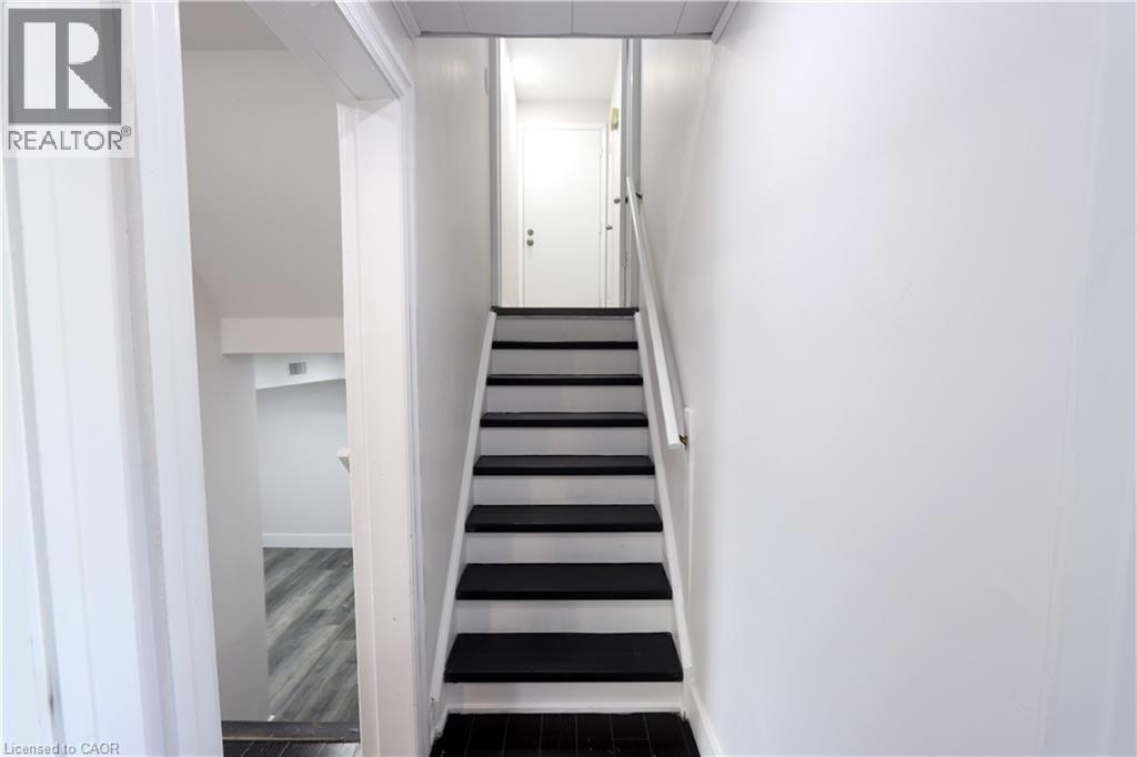 Staircase with contrasting black treads and white risers, framed by a white handrail - 77 Orchard Mill Crescent, Kitchener, ON - Indoor Photo Showing Other Room