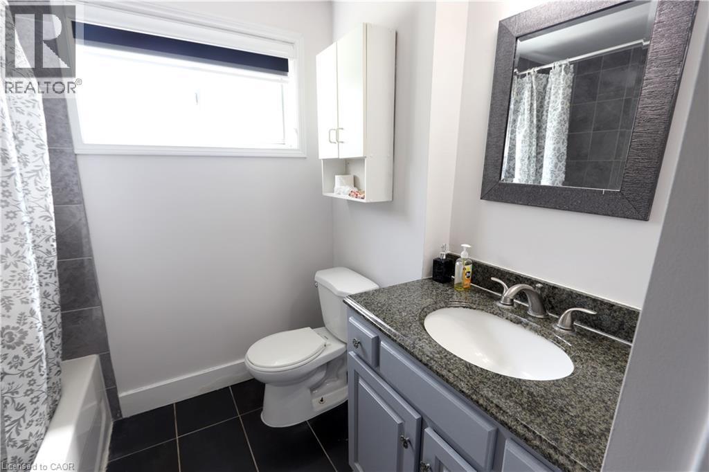Vanity with stone countertop, undermount sink, and brushed nickel fixtures - 77 Orchard Mill Crescent, Kitchener, ON - Indoor Photo Showing Bathroom