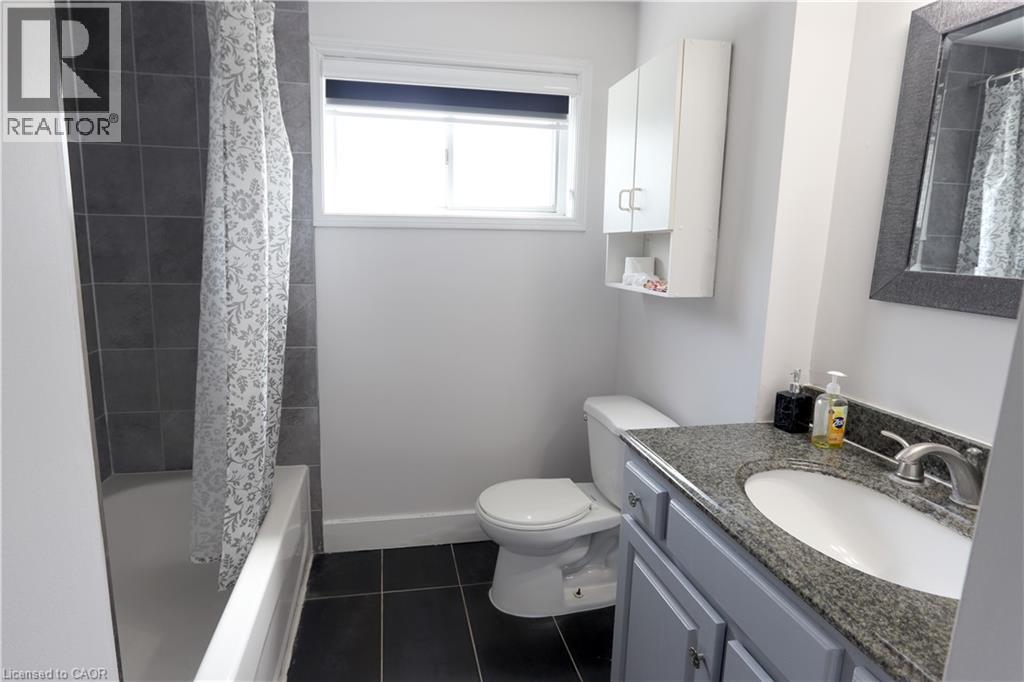 Bathroom featuring a vanity with an integrated sink, granite-style countertop, and grey base cabinetry - 77 Orchard Mill Crescent, Kitchener, ON - Indoor Photo Showing Bathroom