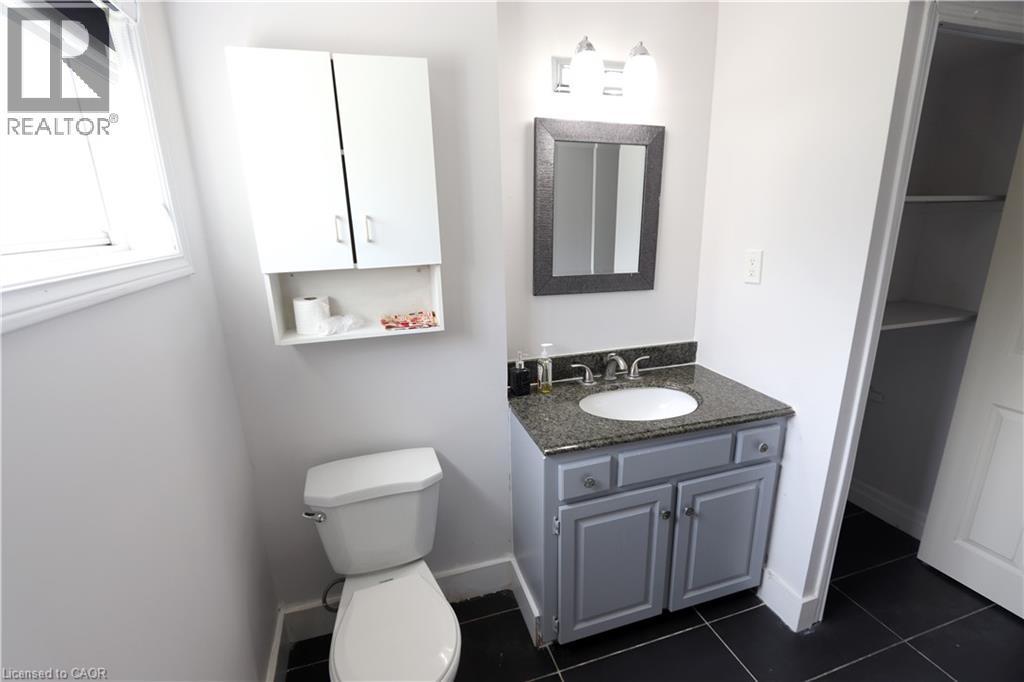 Vanity with a granite countertop, undermount sink, and a framed mirror - 77 Orchard Mill Crescent, Kitchener, ON - Indoor Photo Showing Bathroom