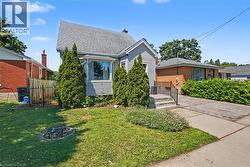 Gabled roofline, light-colored siding, and a prominent bay window -
