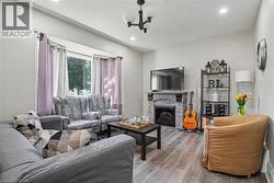 Spacious living area featuring wood-finish flooring, a stone-clad fireplace with mantel, recessed lighting, and a prominent bay window -