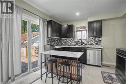 Updated kitchen featuring dark wood cabinetry, a mosaic tile backsplash, stainless steel appliances, and a sliding glass door -
