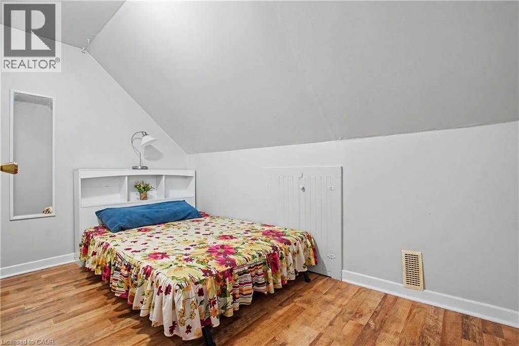 Wood-finish flooring with crisp white baseboards, complemented by a sloped ceiling and light-toned walls - 16 Mercer Road, Cambridge, ON - Indoor Photo Showing Bedroom