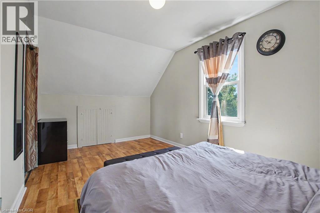 Vaulted ceiling, wood-finish flooring, white window trim, and white bi-fold closet doors - 16 Mercer Road, Cambridge, ON - Indoor Photo Showing Bedroom