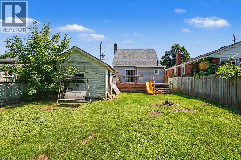 Expansive rear yard featuring a wood deck, wood privacy fencing, and a detached auxiliary building - 16 Mercer Road, Cambridge, ON - Outdoor