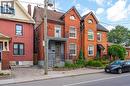 Brick exterior with a peaked roofline, front balcony, and mature landscaping - 128 Hess Street N, Hamilton, ON  - Outdoor With Balcony With Facade 