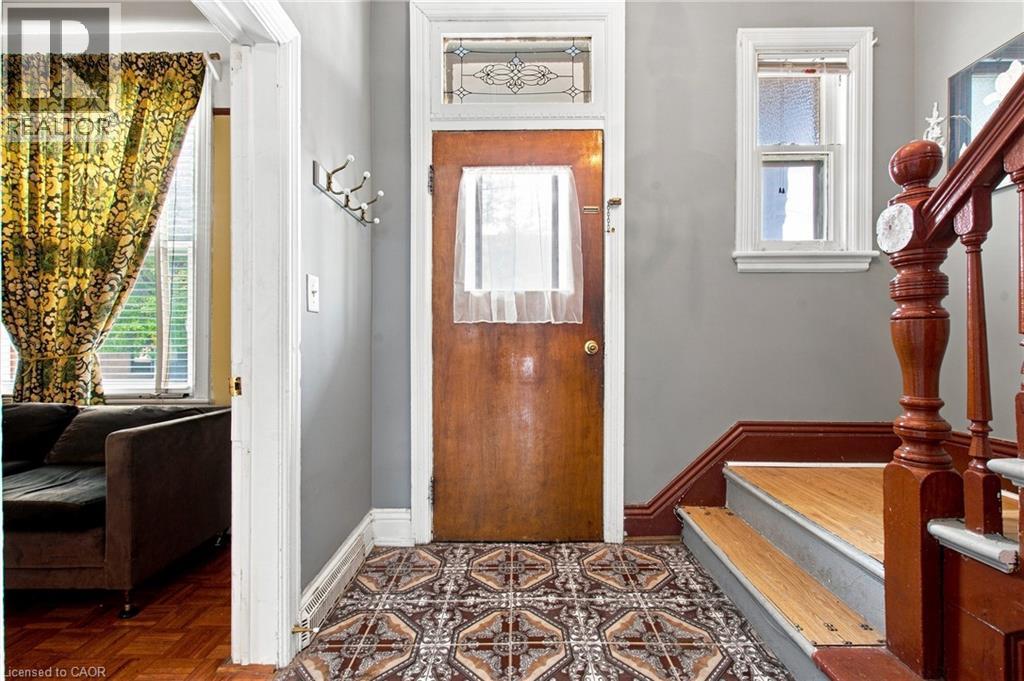 Wood-finish entry door with decorative transom window and patterned floor tiles - 128 Hess Street N, Hamilton, ON - Indoor Photo Showing Other Room