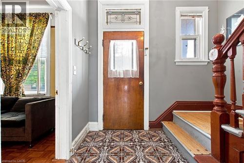 Wood-finish entry door with decorative transom window and patterned floor tiles - 128 Hess Street N, Hamilton, ON - Indoor Photo Showing Other Room