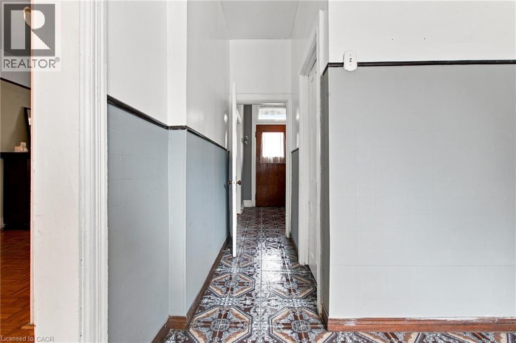 Hallway featuring patterned floor tiling, and a wood-panel door - 128 Hess Street N, Hamilton, ON - Indoor Photo Showing Other Room