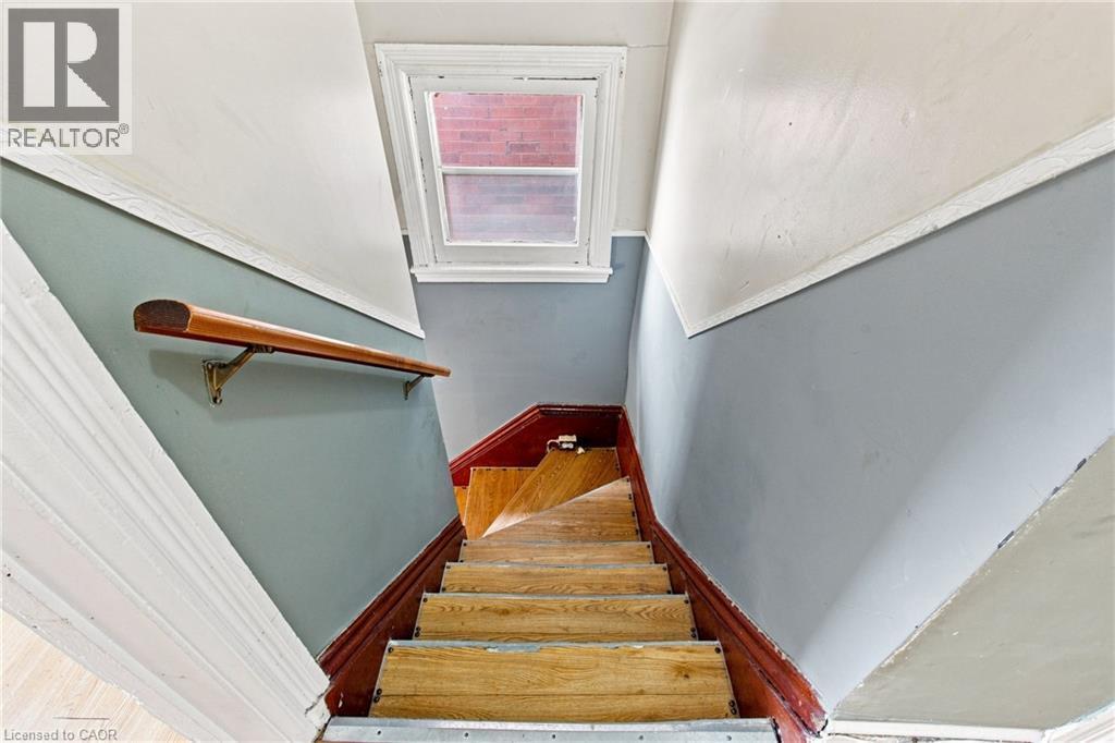 Wood-finish staircase with painted risers, wood handrail, and upper window - 128 Hess Street N, Hamilton, ON - Indoor Photo Showing Other Room