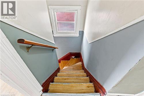 Wood-finish staircase with painted risers, wood handrail, and upper window - 128 Hess Street N, Hamilton, ON - Indoor Photo Showing Other Room