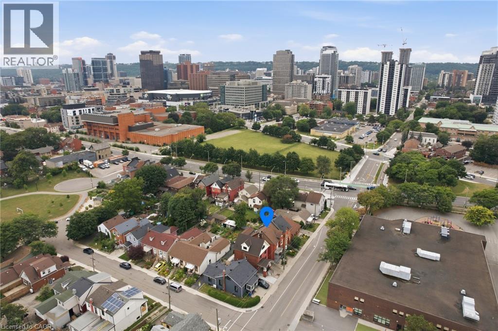 Urban setting featuring mature trees, residential street, and city skyline - 128 Hess Street N, Hamilton, ON - Outdoor With View