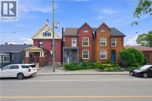 Brick exterior with contrasting trim, front porch with columns, gabled roofline, and landscaped front garden - 128 Hess Street N, Hamilton, ON - Outdoor With Balcony With Facade