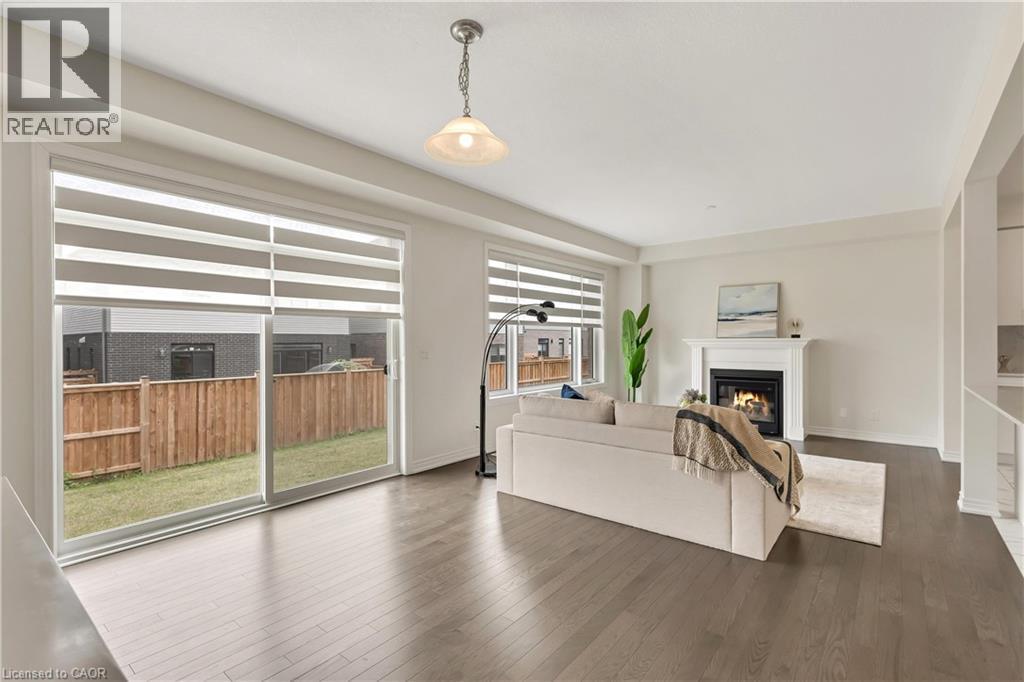 Spacious living area featuring wood-finish flooring, a white mantel fireplace, and a sliding glass door to the backyard - 285 Broadacre Drive, Kitchener, ON - Indoor With Fireplace