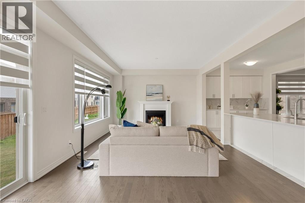 Open-concept living space featuring wood-finish flooring, a fireplace with a mantel, and large windows - 285 Broadacre Drive, Kitchener, ON - Indoor With Fireplace