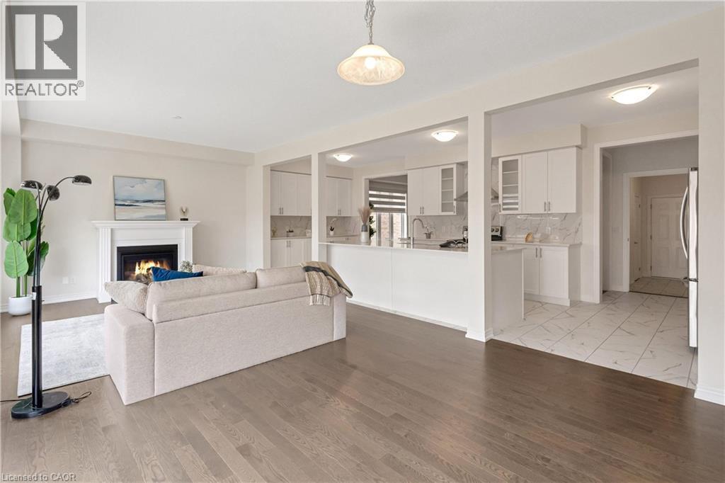 Hardwood flooring throughout, fireplace with a mantle, white cabinetry, integrated kitchen appliances, and tile flooring - 285 Broadacre Drive, Kitchener, ON - Indoor With Fireplace