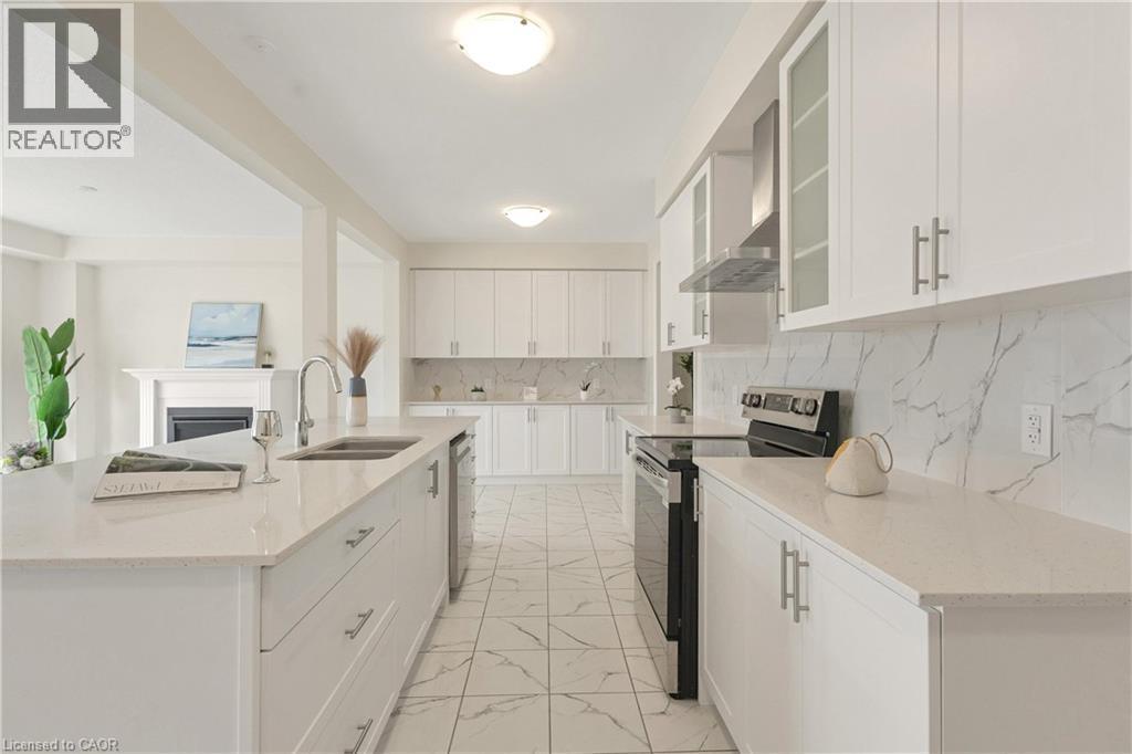 Contemporary kitchen featuring white cabinetry, light-toned countertops, a stainless steel range hood, and a dual-basin sink - 285 Broadacre Drive, Kitchener, ON - Indoor Photo Showing Kitchen With Double Sink
