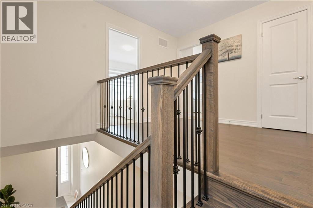 Hardwood flooring with a wood-finish staircase and black wrought iron balusters - 285 Broadacre Drive, Kitchener, ON - Indoor Photo Showing Other Room