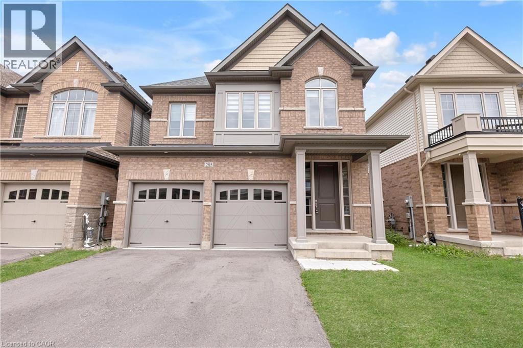 Brick exterior with stone accents, covered front entry, two-car garage with arched window details, and a paved driveway - 285 Broadacre Drive, Kitchener, ON - Outdoor With Facade