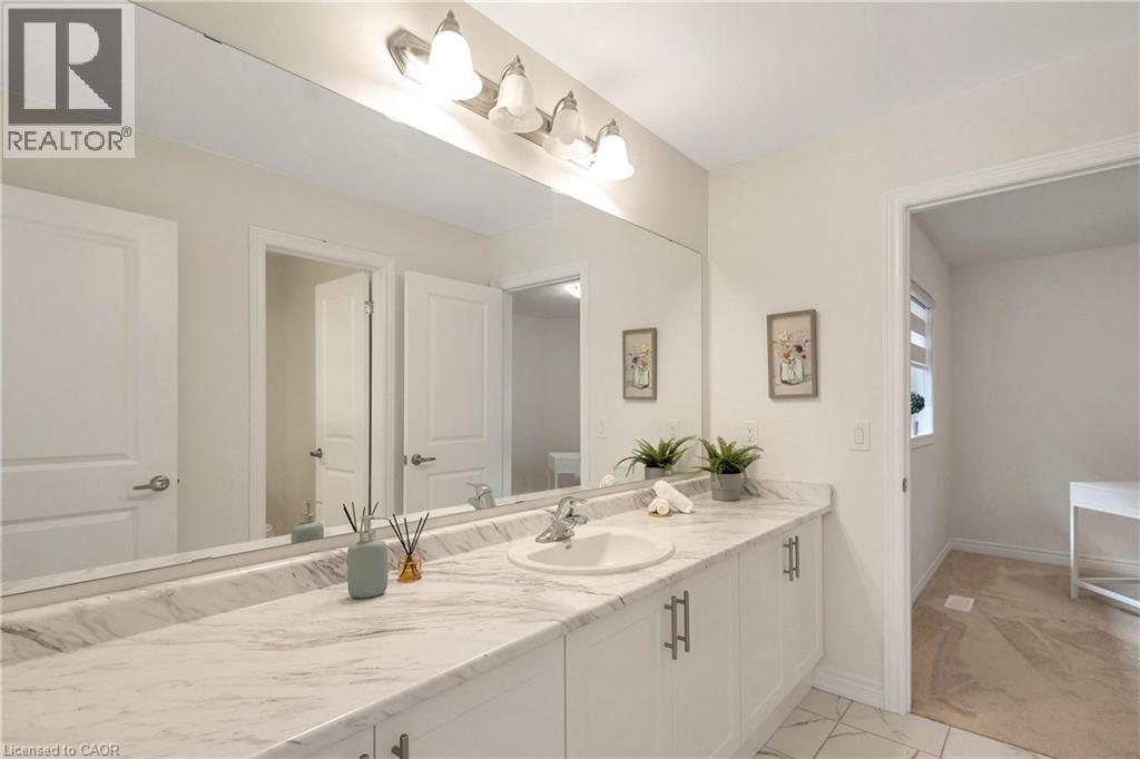 Extended vanity featuring a single basin, stone-finish countertop, and white cabinetry with brushed nickel hardware - 285 Broadacre Drive, Kitchener, ON - Indoor Photo Showing Bathroom