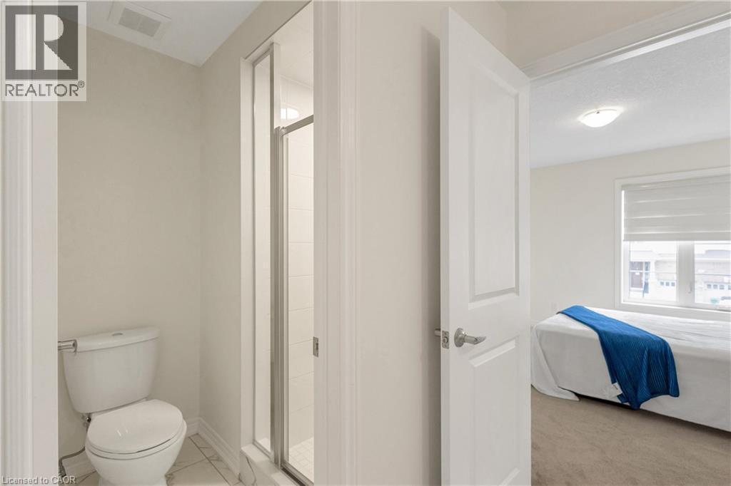White toilet with a glass-enclosed shower, white tile flooring, and a flat panel door - 285 Broadacre Drive, Kitchener, ON - Indoor Photo Showing Bathroom