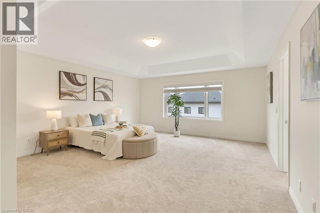 Spacious room featuring a tray ceiling, wall-to-wall carpeting, wide window, and neutral wall color - 285 Broadacre Drive, Kitchener, ON - Indoor