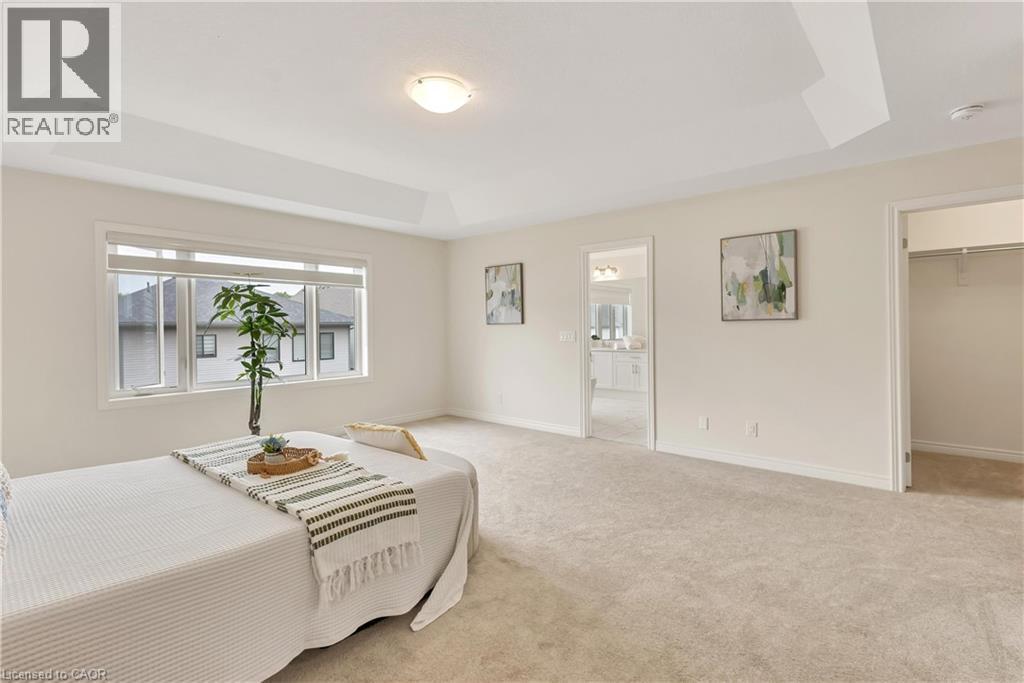 Spacious room with a tray ceiling, large windows, light-toned carpet flooring, and a walk-in closet - 285 Broadacre Drive, Kitchener, ON - Indoor