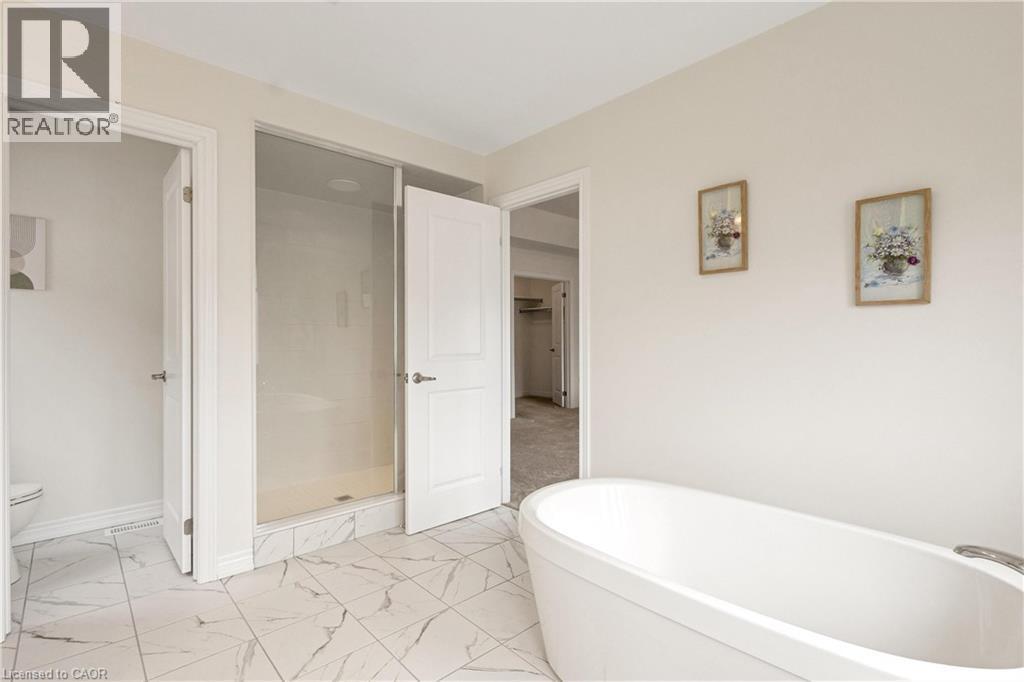 Freestanding soaking tub, glass-enclosed shower, white paneled doors, and large format floor tiling - 285 Broadacre Drive, Kitchener, ON - Indoor Photo Showing Bathroom