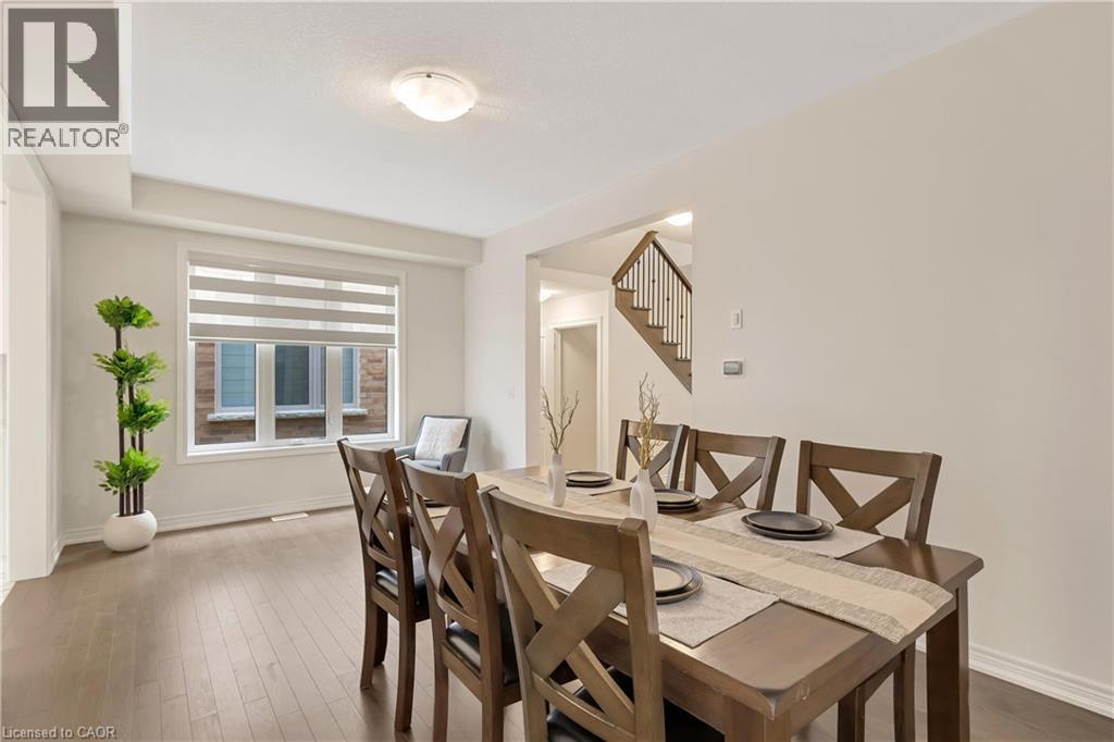 Hardwood-style flooring throughout, large window with layered blinds, recessed ceiling detail, flush mount lighting, and wood staircase with dark railing - 285 Broadacre Drive, Kitchener, ON - Indoor Photo Showing Dining Room