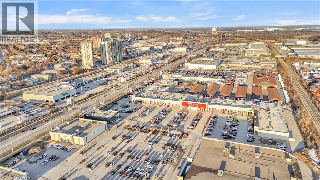 Aerial perspective of a commercial district with multiple retail establishments, extensive surface parking, and multi-lane roadways - 589 Fairway Road S, Kitchener, ON
