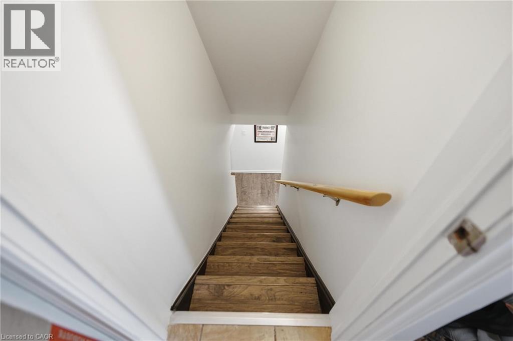 Stairs to basement featuring wood-finish treads, a light wood handrail, and white painted walls - 481 Upper Gage Avenue, Hamilton, ON - Indoor Photo Showing Other Room