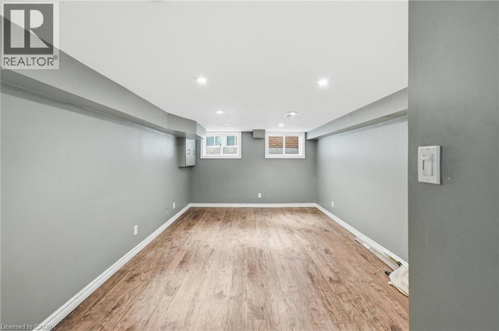 Finished living room with wood-finish flooring, recessed lighting, and two windows providing natural light - 481 Upper Gage Avenue, Hamilton, ON - Indoor Photo Showing Other Room