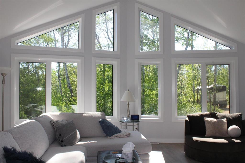 The living room features vaulted ceilings and this stunning wall of windows. Not a bad view... - 7 Dalvik Road, Gimli Rm, MB - Indoor Photo Showing Living Room