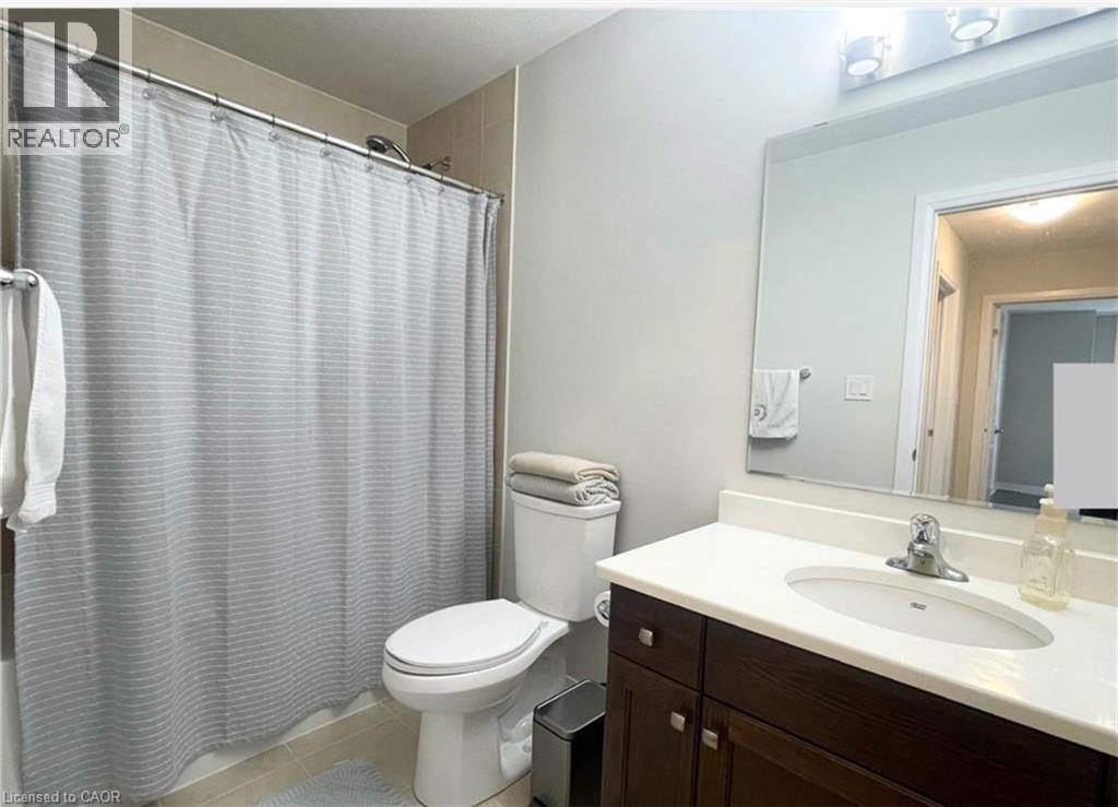 White vanity countertop with integrated sink, dark wood-finish cabinetry, and a chrome faucet - 17 Visionary Avenue, Kitchener, ON - Indoor Photo Showing Bathroom