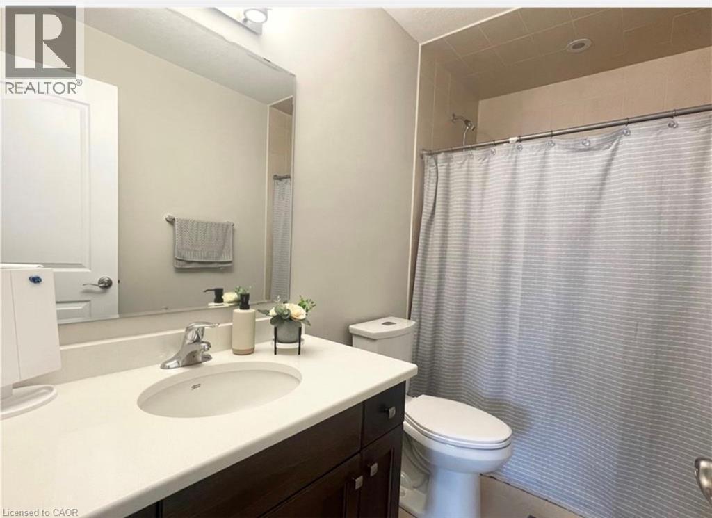 Vanity with a built-in sink and countertop, large wall-mounted mirror, and a shower with tiled surround - 17 Visionary Avenue, Kitchener, ON - Indoor Photo Showing Bathroom