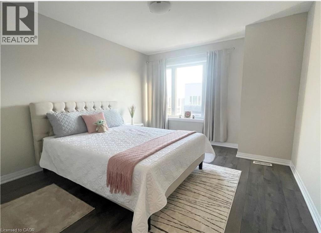 Neutral wall paint, wood-finish flooring, and a window with white trim - 17 Visionary Avenue, Kitchener, ON - Indoor Photo Showing Bedroom